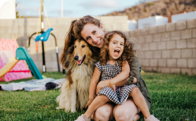 Mother, daughter, and dog, sitting in a back yard on a sunny day.