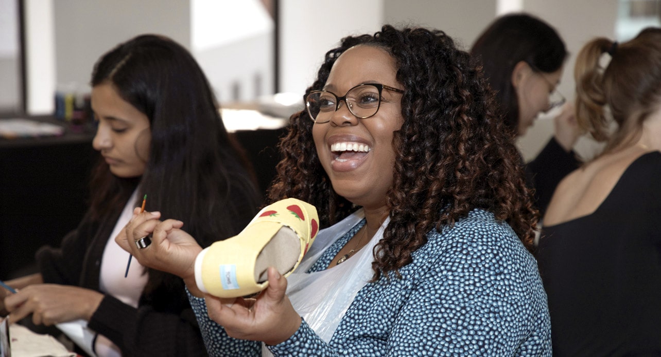 A FOX employee decorating a shoe and laughing during a company event.