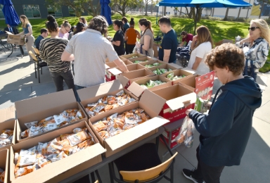 A group of employees lining up around tables holding boxes of chips.